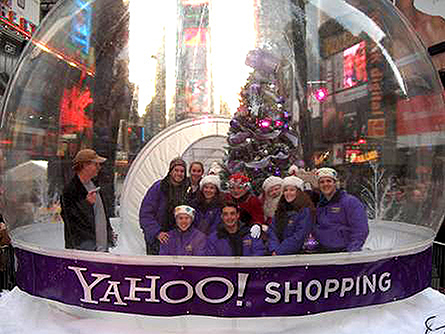 Group of guests inside Absolute Hollywood airlock tunnel entry snow globe at Times Square New York — Yahoo! Shopping brand activation with Manhattan skyline visible