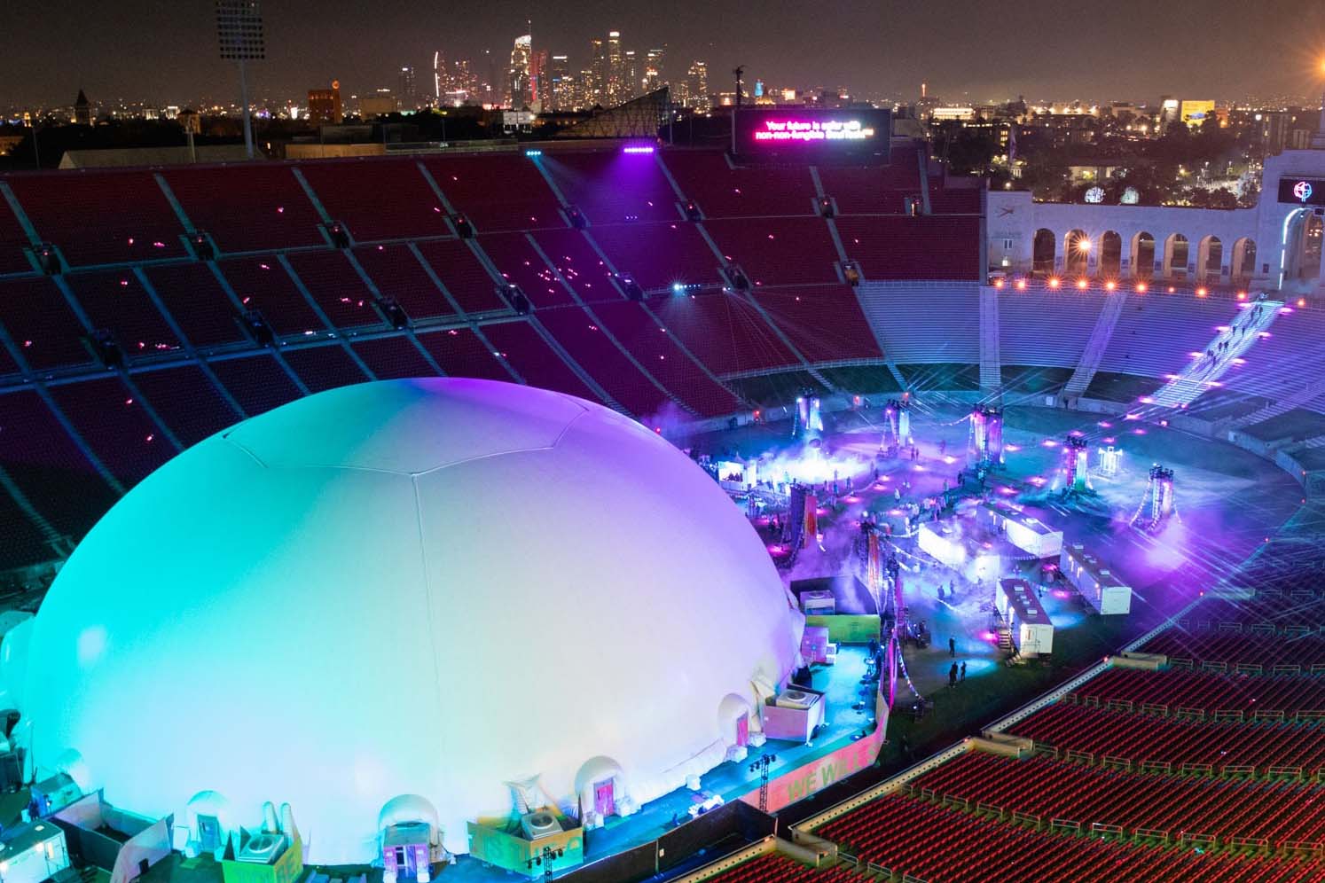 Absolute Hollywood concert dome fully inflated at night inside LA Memorial Coliseum during Skrillex event 2015, Los Angeles skyline visible behind stadium