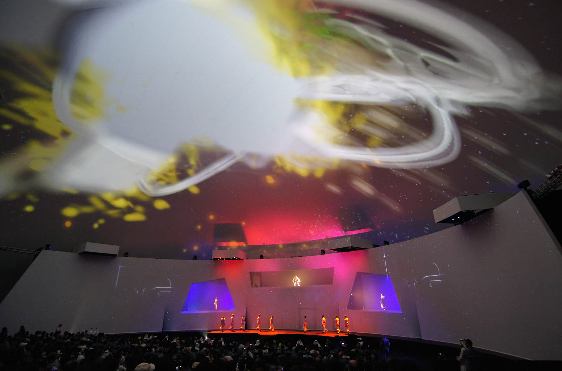 Interior of Absolute Hollywood Galactic projection dome during EMAL inauguration Abu Dhabi 2011, 360 degree fulldome projection active overhead with live performers on stage and large audience seated
