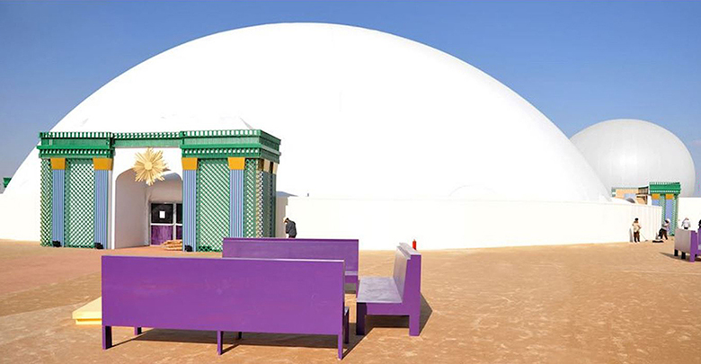 Projection dome exterior daytime — large white inflatable Celestial dome fully erected in Doha Qatar desert with ornate entry structure and StratoSphere sphere visible alongside