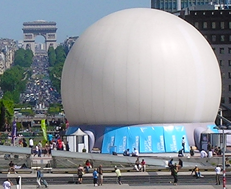 Projection dome exterior daytime — large white inflatable projection dome deployed on Paris Champs-Élysées with Arc de Triomphe visible in background, Athens tourism campaign France