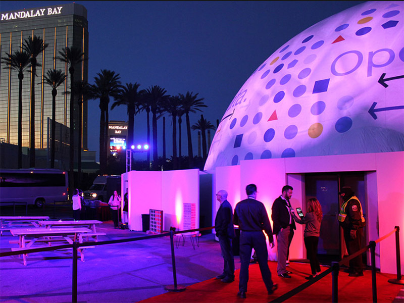Projection dome exterior — IBM Open for Data corporate event, branded fulldome projection on hemispherical surface, guests entering through airlock entry, Mandalay Bay Las Vegas in background at dusk