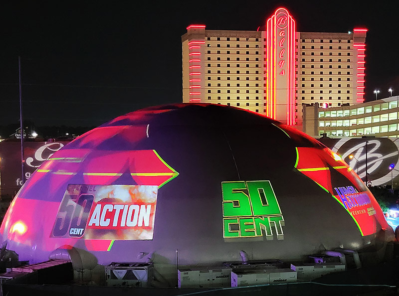 Projection dome exterior night — full 360 degree video projection on hemispherical dome surface, 50 Cent Humor and Harmony Festival, Bally's Shreveport Louisiana casino in background