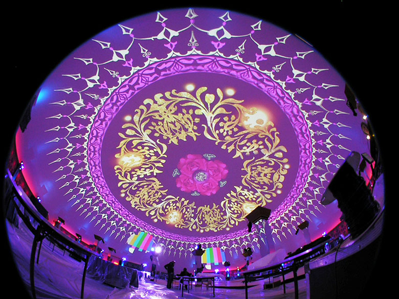 Projection dome fisheye interior view — full 360 degree hemispherical surface covered in purple and gold mandala fulldome projection, projectors visible around perimeter ring, Qatar royal wedding