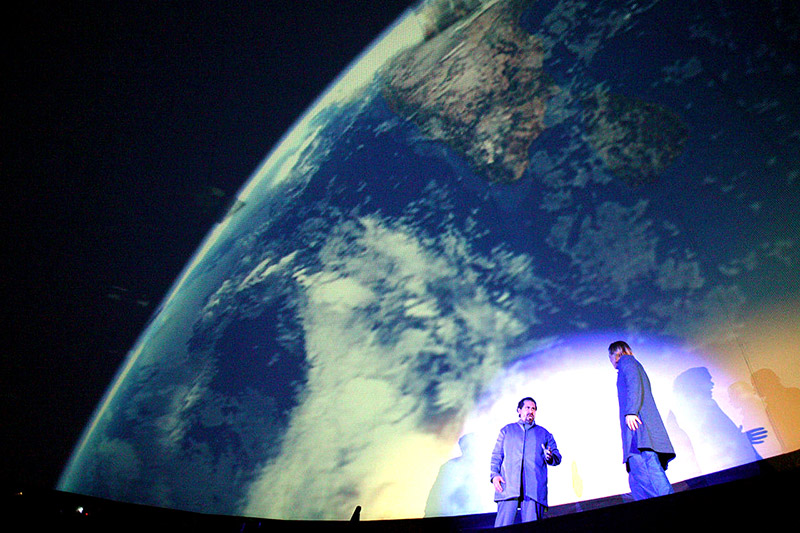 Projection dome interior — live performers on stage with full hemispherical Earth fulldome projection covering entire dome surface, Einstein Space Opera Speed of Light, Berlin Germany