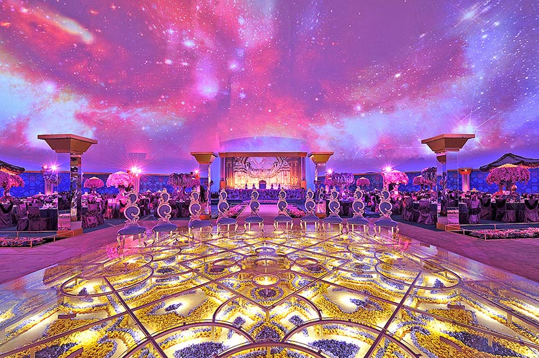 Projection dome interior — royal wedding gala with galaxy fulldome projection overhead, illuminated dance floor in foreground, stage and banquet tables visible throughout, Doha Qatar