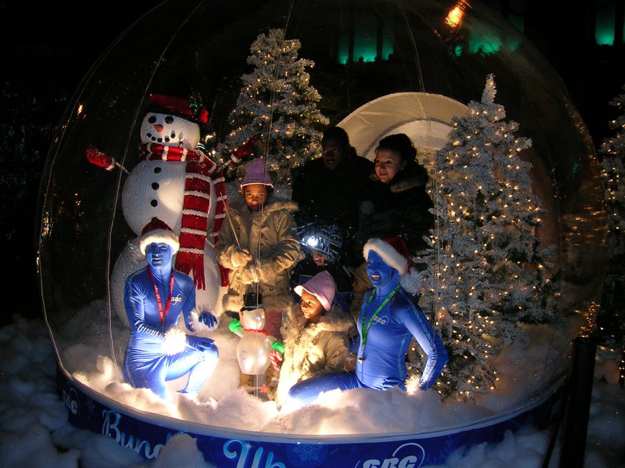 Snow globe photo booth rental lit at night for an SBC winter activation — guests posing inside an Absolute Hollywood globe