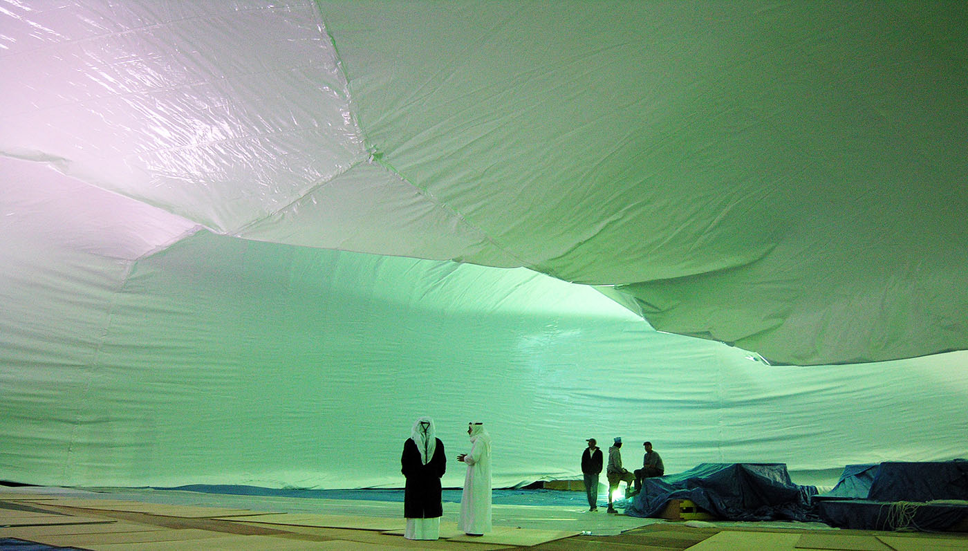 Dome fabric rising at night with crew working the perimeter — a 200 ft large projection dome taking shape mid-inflation