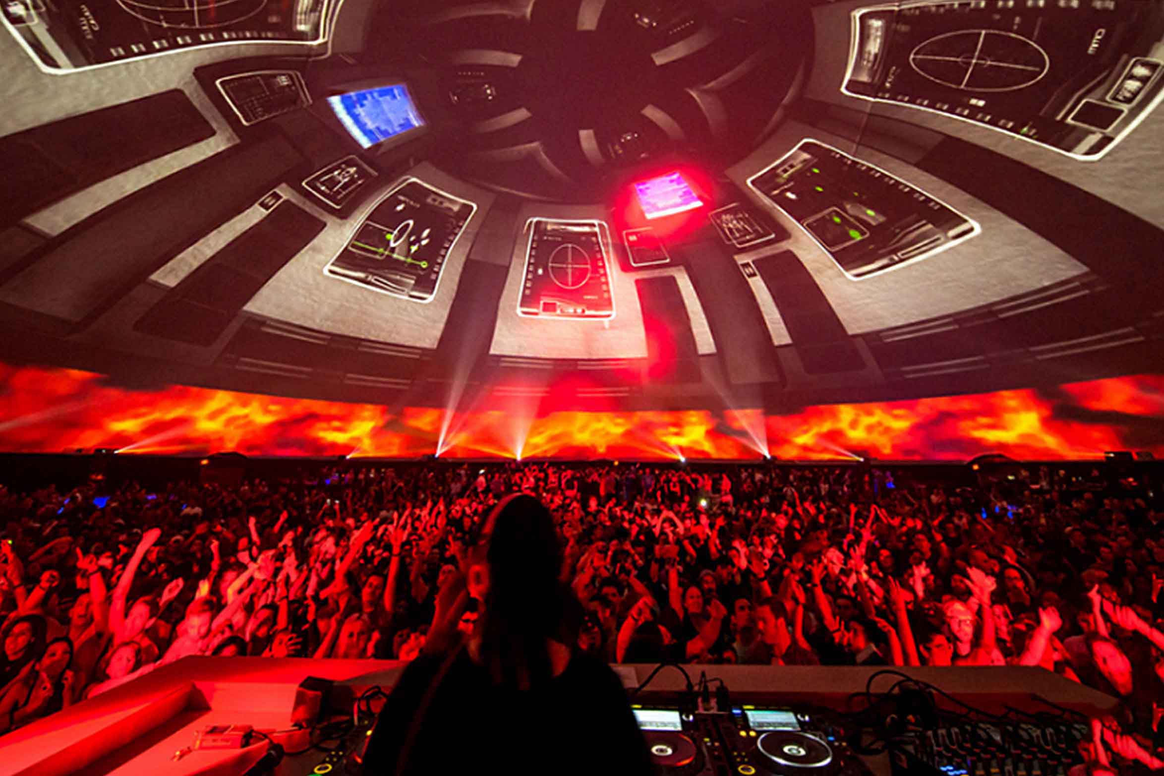DJ silhouetted before a wall of red fulldome imagery wrapping the crowd inside the Skrillex dome at the LA Memorial Coliseum