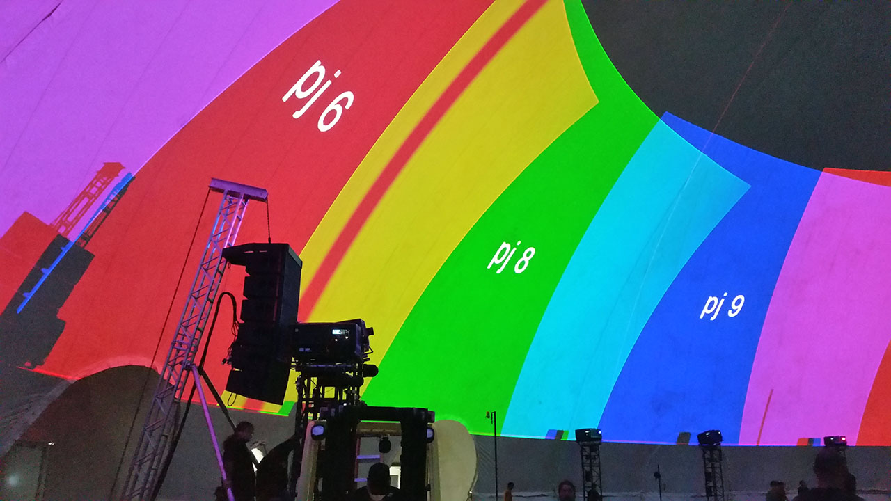 Projector rig aimed at a rainbow of numbered test channels across the dome surface during calibration