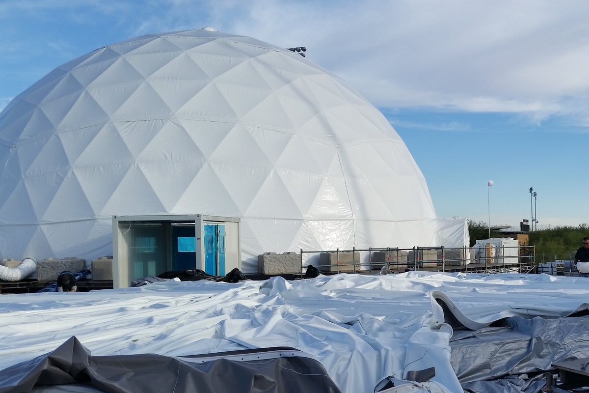 70 ft geodesic dome standing beside an air dome skin laid out for inflation at The Marvel Experience eight-dome campus