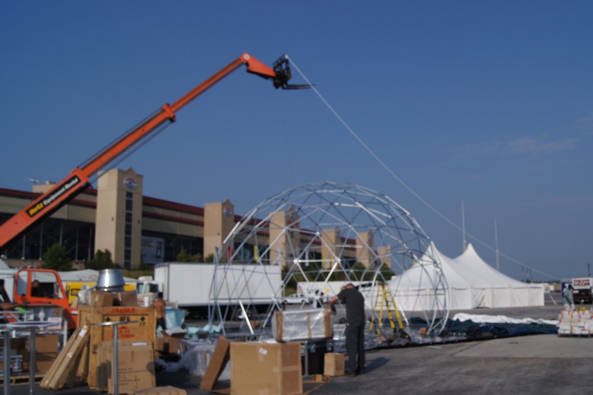 Bare aluminum geodesic dome frame under assembly with a telehandler on site at Atlanta Motor Speedway, 2011