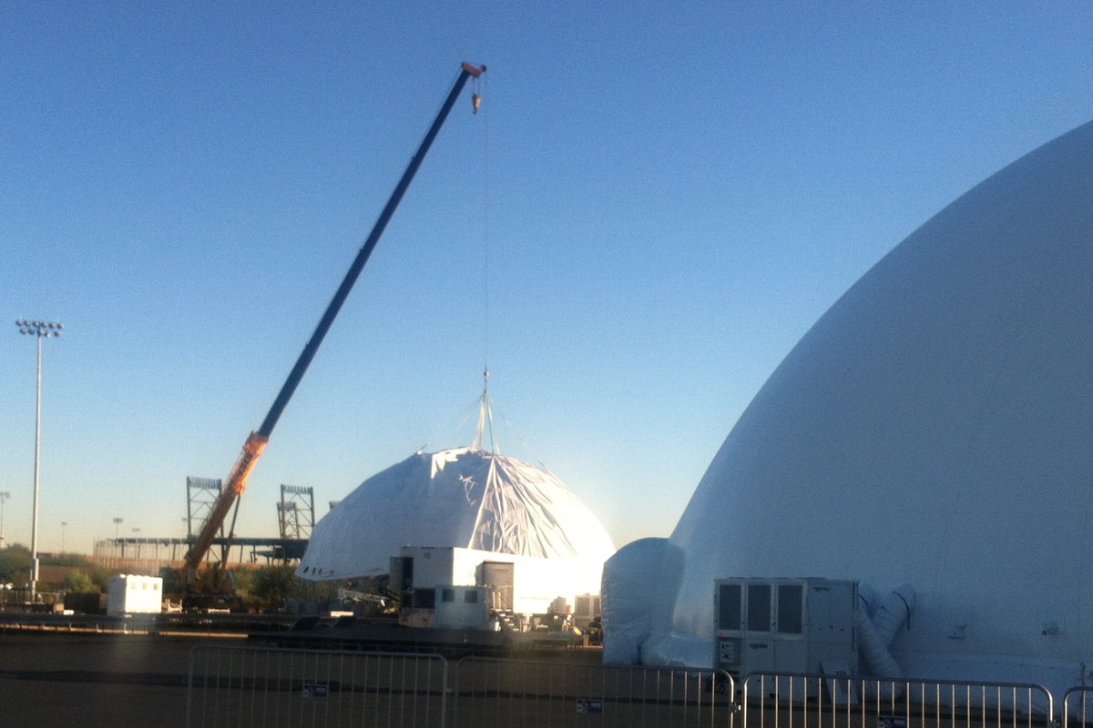 Crane lifting the cover over a 70 ft geodesic dome structure beside a fully inflated air dome at The Marvel Experience