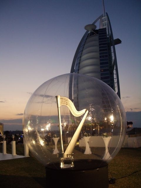 Giant snow globe holding an illuminated harp at sunset beside the Burj Al Arab hotel in Dubai, United Arab Emirates