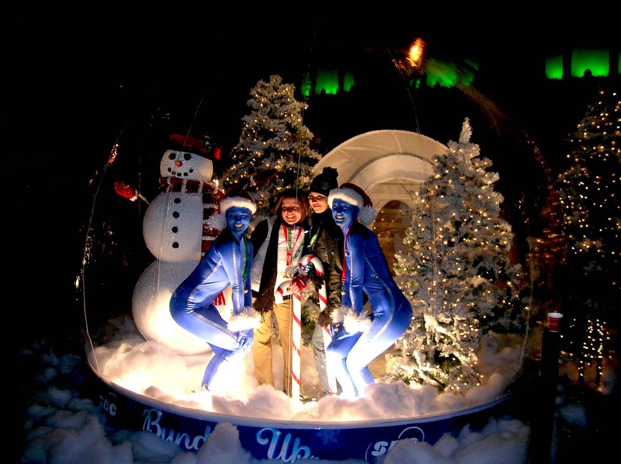 Guests seated inside a blue-lit life size snow globe rental with a snowman and flocked trees at a brand activation