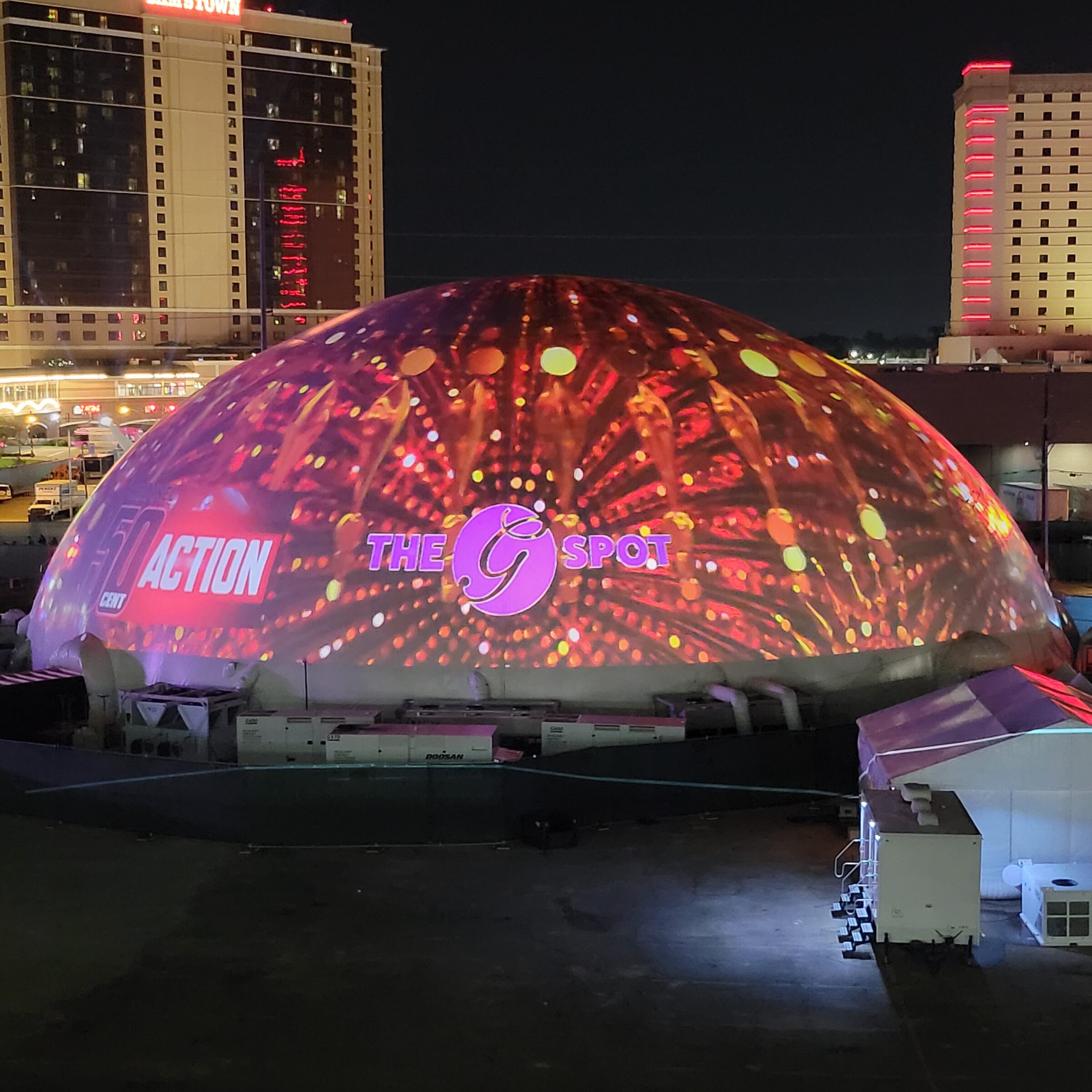 Elevated night view of a 160 ft projection dome rental covered in projected fireworks at the Humor and Harmony festival, with the Shreveport casino skyline behind.