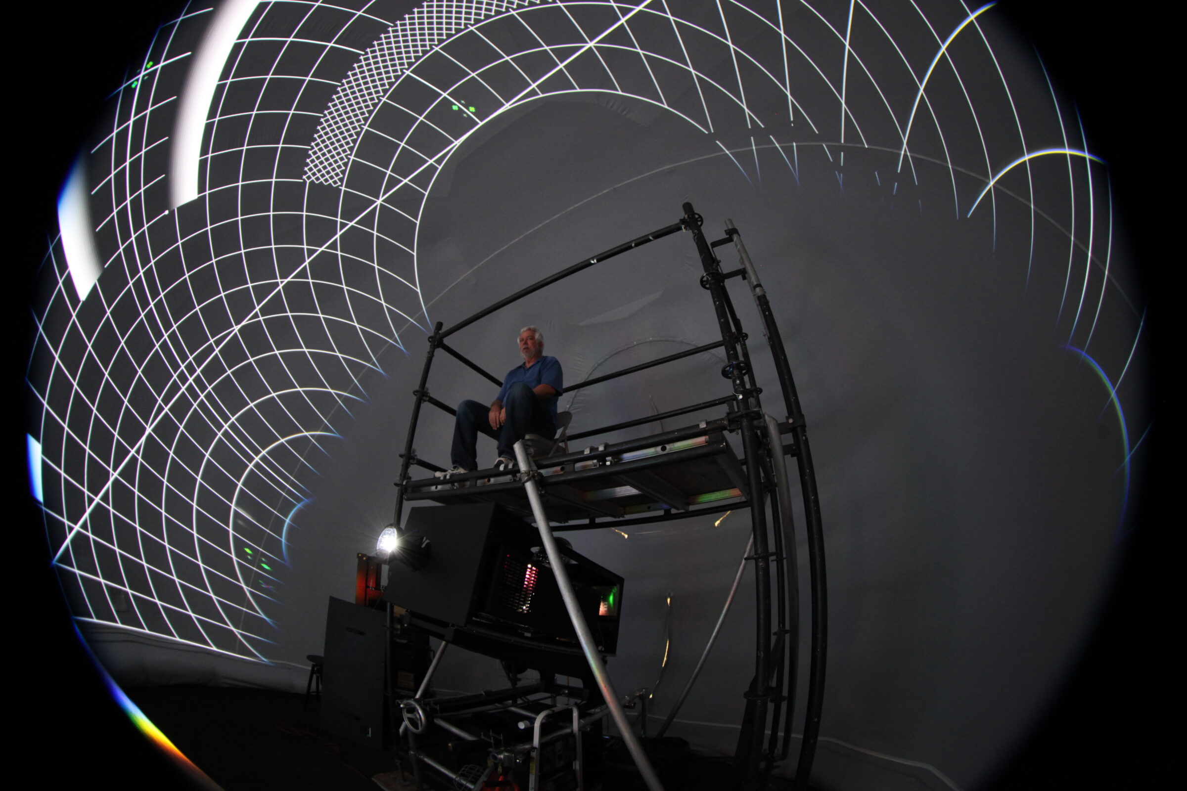Technician’s multi-projector calibration rig aligning imagery inside a projection dome rental during pre-show setup.