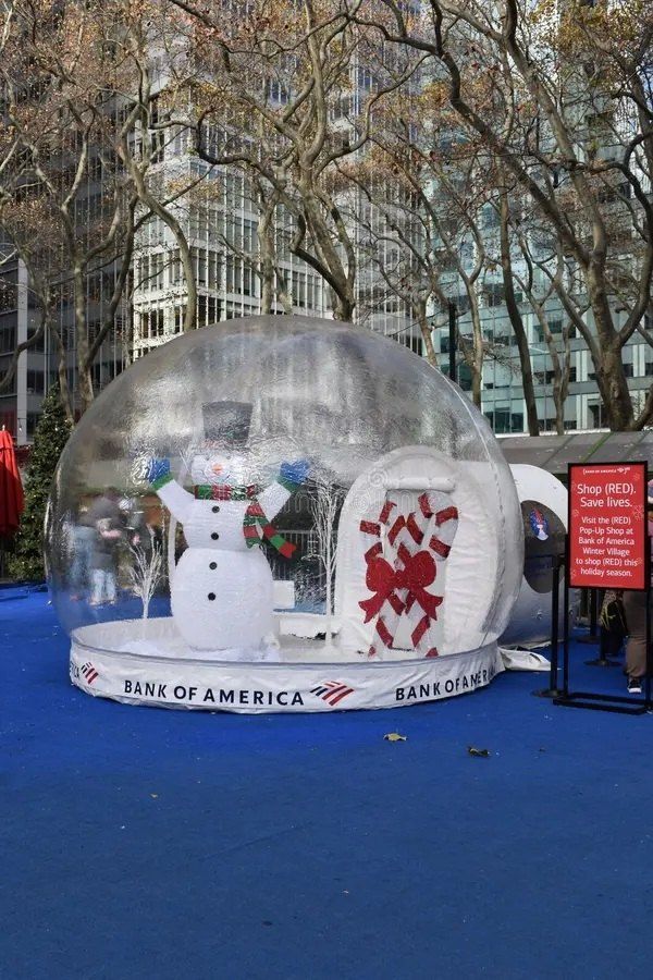 Snow globe rental with a snowman scene inside and an entry tunnel attached at the side, on blue carpet in New York