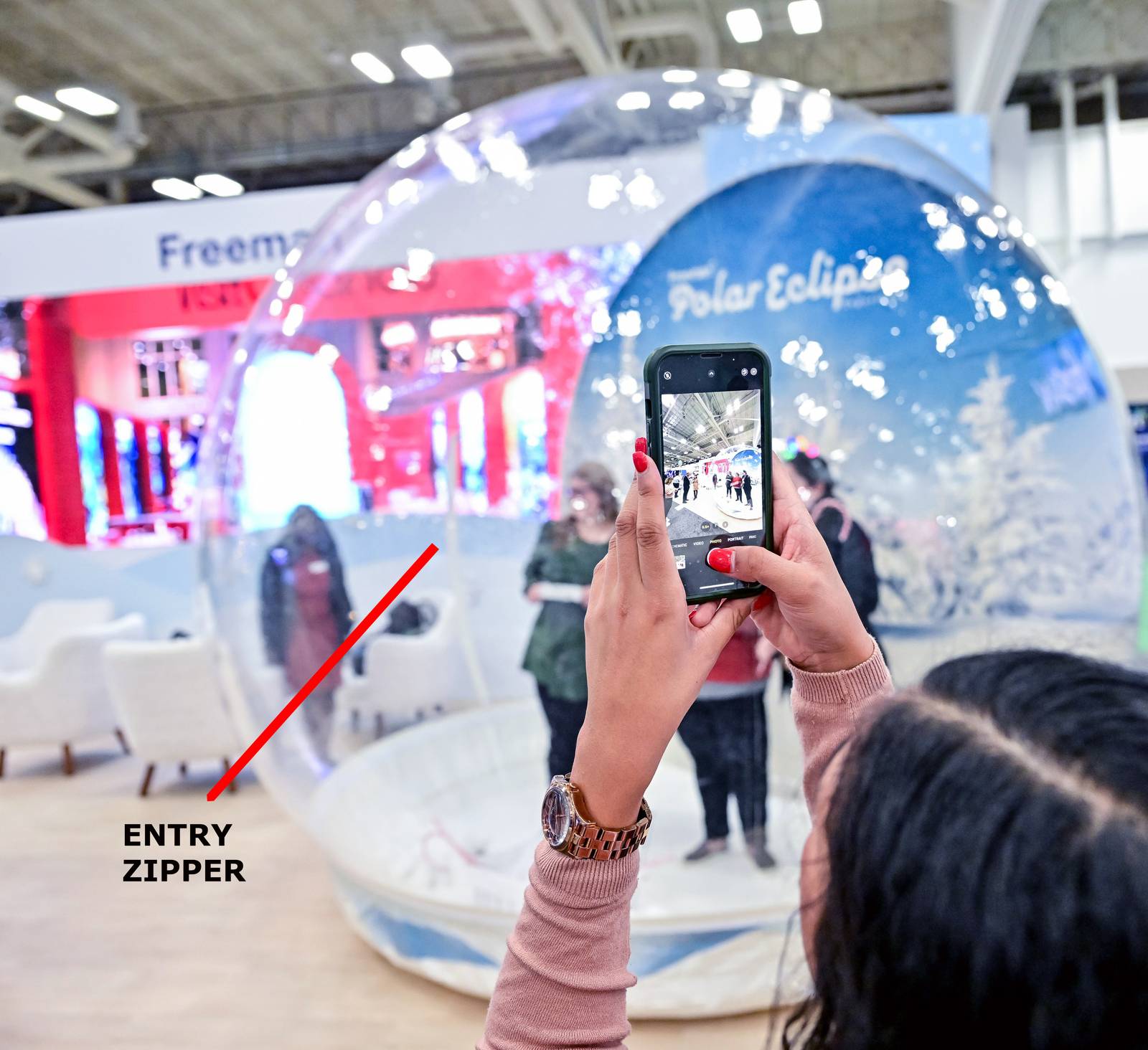 Guest photographing the winter scene from inside a zipper entry snow globe at a Freeman convention, 2022