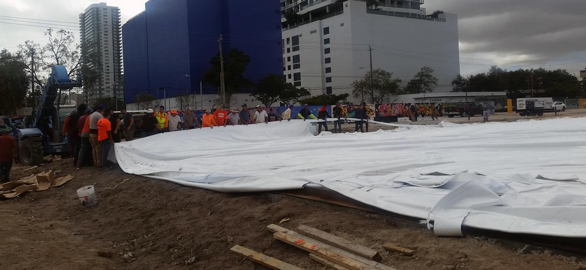 Crew unrolling the fabric envelope of an air-supported dome on site before inflation