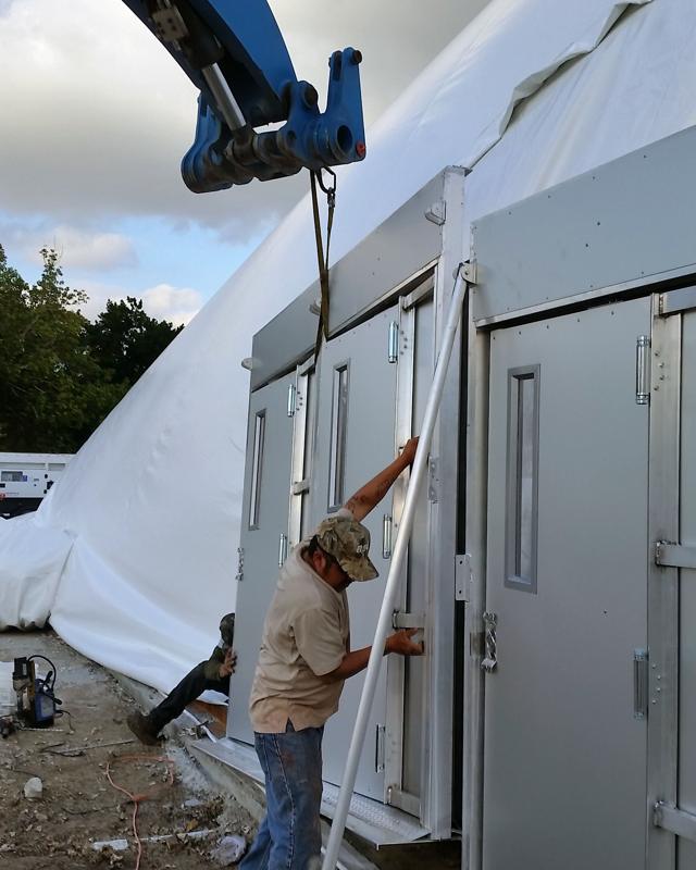 Installer fitting the two-door airlock entry system to an inflatable dome