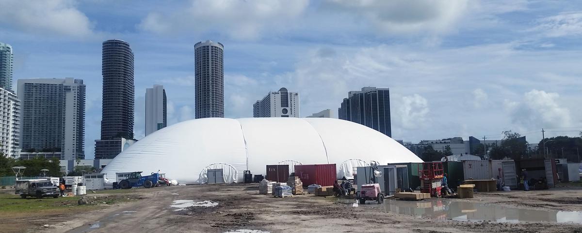 Inflatable projection dome fully inflated on an open lot with the Miami skyline behind
